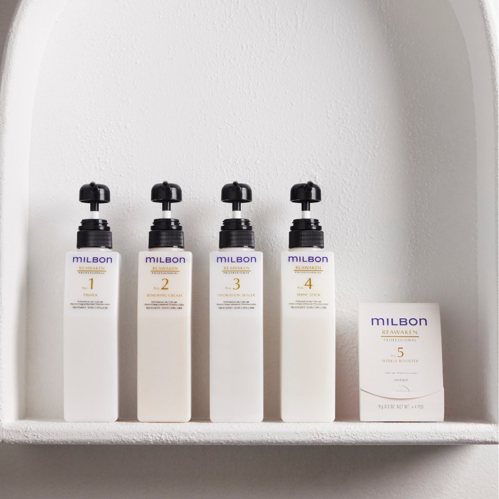 MILBON Reawaken Professional Head Spa products displayed on a sleek salon counter, featuring Renewing Shampoo, Shine Rejuvenating Emollient Oil, and Renewing Primer for vibrant, hydrated hair.